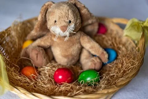 Stuffed easter bunny in hay basket and eggs. Stock Photos