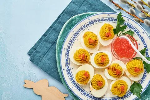 Stuffed eggs with red caviar and paprika on blue plate for appetizer easter t Stock Photos