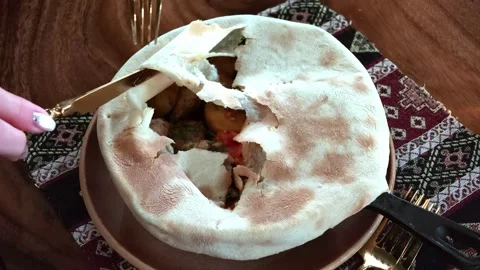 Stuffed flatbread with vegetables and meat being sliced beside decorative Video stock 343628867