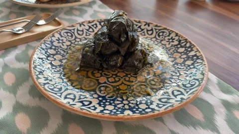 Stuffed grape leaves piled on patterned plate as a Mediterranean dish backg.. Video stock 332303967