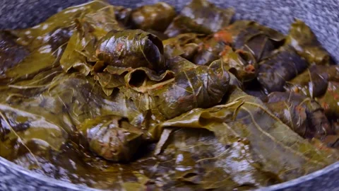 Stuffed grape leaves with rice and meat rotates on a board Stock Footage 248323010