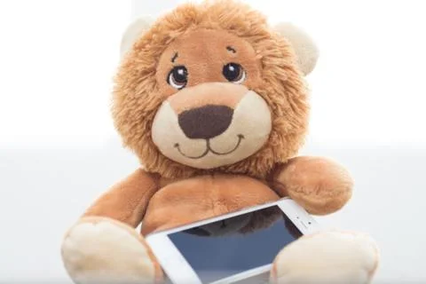 Stuffed lion on white background with cellphone Stock Photos