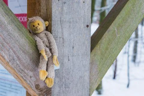 Stuffed monkey between wooden beams, adorable cuddle toy for kids and adults Stock Photos
