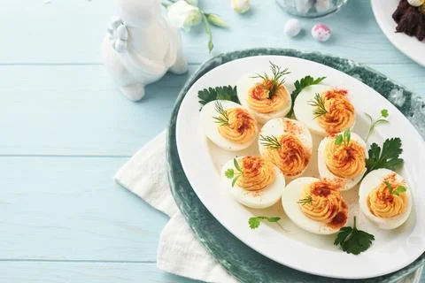 Stuffed or deviled eggs with paprika and parsley on blue plate for easter tab 스톡 사진