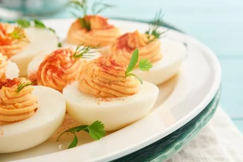 Stuffed or deviled eggs with paprika and parsley on blue plate for easter tab Stock Photos