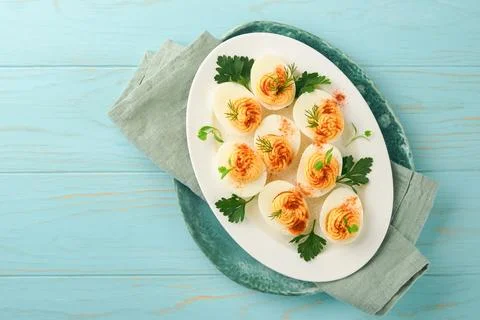 Stuffed or deviled eggs with paprika and parsley on blue plate for easter tab Stock Photos