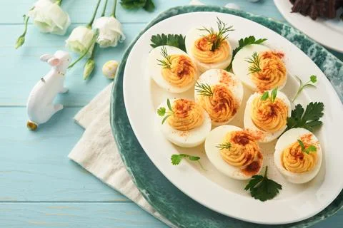 Stuffed or deviled eggs with paprika and parsley on blue plate for easter tab 스톡 사진