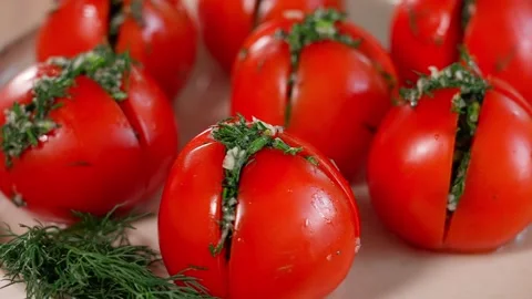 Stuffed red tomatoes with herbs rotate in a circle in a plate. Stock Footage 253987132