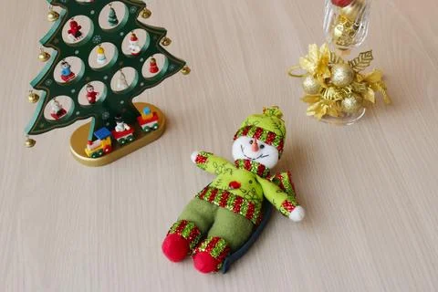 Stuffed snowman lying down beside a Christmas toy tree. Stock Photos