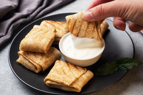 Stuffed thin pancakes rolled into rolls are grilled on a black plate. Panca.. Foto stock