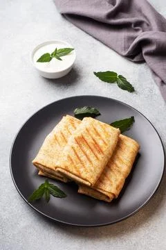 Stuffed thin pancakes rolled into rolls are grilled on a black plate with min Stock-Fotos