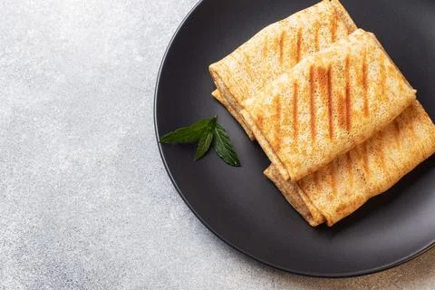 Stuffed thin pancakes rolled into rolls are grilled on a black plate with m.. Stock-Fotos