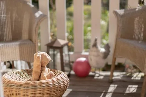 Stuffed toy easter bunny sitting on a straw chair on the veranda, looking to Stock Photos