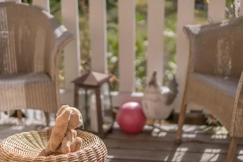 Stuffed toy easter bunny sitting on a wicker chair on the veranda in the sun. Foto stock