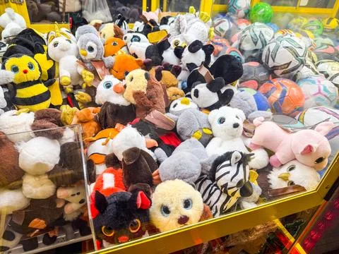 Stuffed toys inside a claw machine. Childhood, leisure, play and amusement in Stockfoto's