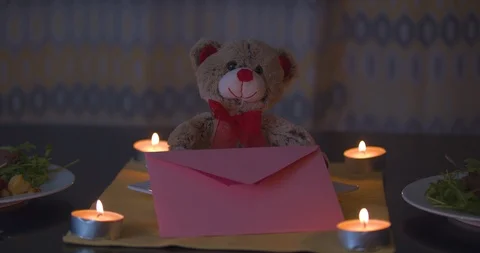 Stuffed Valentines Bear Sitting on a Table with Candles in the Background Stock Footage 101374250