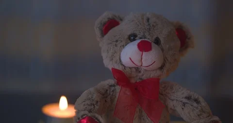 Stuffed Valentines Bear Sitting on a Table with Candles in the Background Stock Footage 101375091