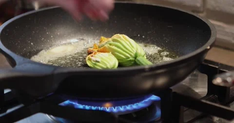 Stuffed zucchini flowers are fried in pan on gas stove. Video stock 196140331