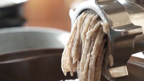 Stuffing comes out through a sieve of a meat grinder. Meat grinder close-up. A Stock Footage 132094480