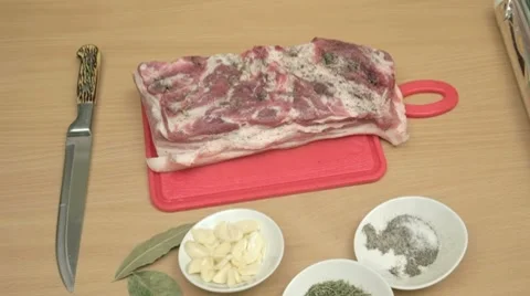 Stuffing thin slices of garlic in salted and peppered bacon. Stock Footage 7740897