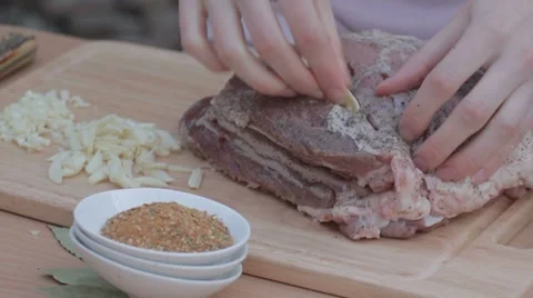 Stuffing thin slices of garlic in salted and peppered pork Stock-Footage 7766797