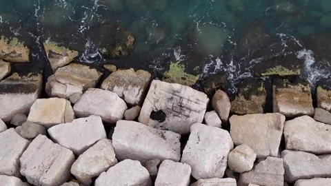 A stunning aerial drone view of waves crashing against rocks Stock Footage 296176884