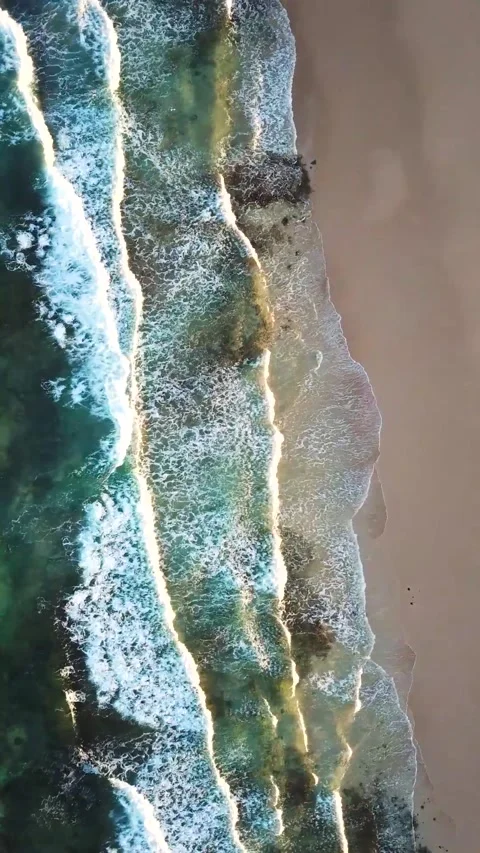 Stunning aerial top-down view of turquoise ocean waves with white foam gently Stock Footage 344820457
