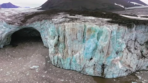 Stunning aerial view of a massive glacier and ice cave along a mountainous Stock Footage 343696598