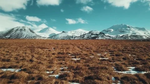 Stunning Aerial View of Snow-Capped Mountains and Golden Fields Stock Footage 323301563