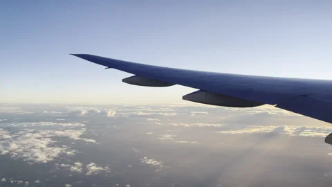 Stunning airplane wing frames endless blue sky over sunlit cloud ocean Stock Footage 337945891