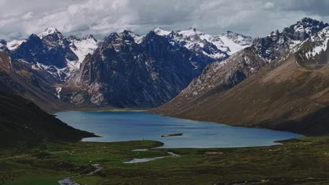 Stunning Alpine Lake Reflecting Rugged Snow-capped Peaks Under Cloudy Sky China Stock Footage 346336445
