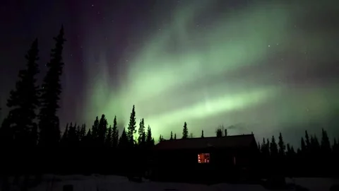 Stunning aurora borealis seen over a cabin nestled among a tranquil forest. Stock Footage 310029911