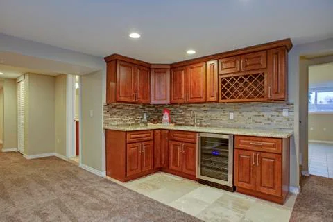 Stunning basement interior boasts a nice wet bar composed of wood shaker cabi Stock Photos