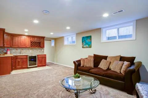 Stunning basement interior boasts a nice wet bar composed of wood shaker cabi Stock Photos