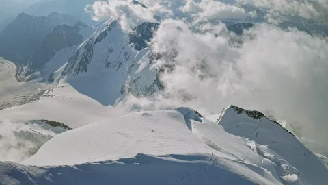 Stunning birds eye view,climbers on snow mountain top,great clouds around summit Stock Footage