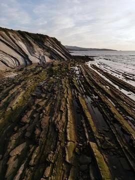 A stunning coastal landscape featuring dramatic rock formations with layers s Stock Photos