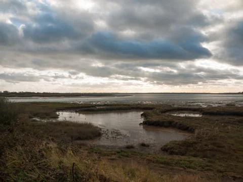 Stunning dramatic cloud sky over estuary lake river ocean coastline landscape Stock Photos