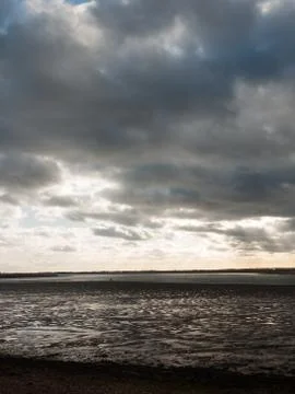 Stunning dramatic cloud sky over estuary lake river ocean coastline landscape Stock Photos