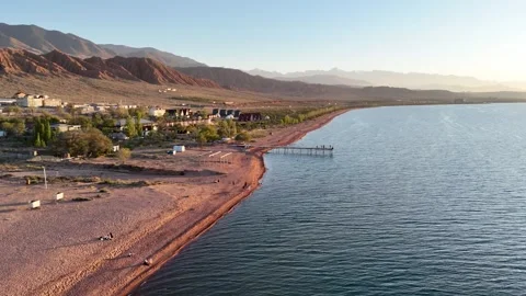 Stunning drone view of Issyk-Kul Lake at sunset, showcasing golden skies Stock Footage 328943796