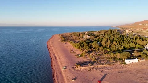 Stunning drone view of Issyk-Kul Lake at sunset, showcasing golden skies Stock Footage 328943898