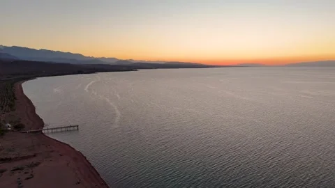 Stunning drone view of Issyk-Kul Lake at sunset, showcasing golden skies Stock Footage 328944120