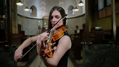 Stunning female violinist performs in a church in black dress 4k Stock Footage