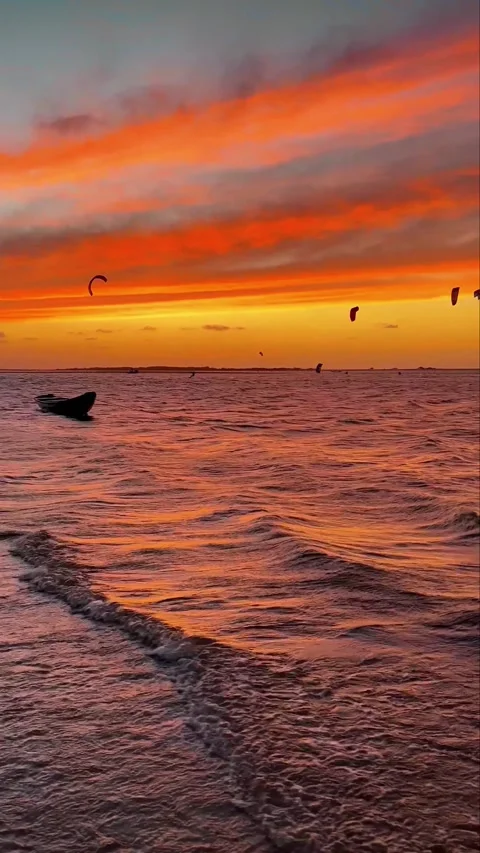 Stunning Fire Sunset Over the Ocean with Kitesurfers and Small Boat Stock Footage 332039861