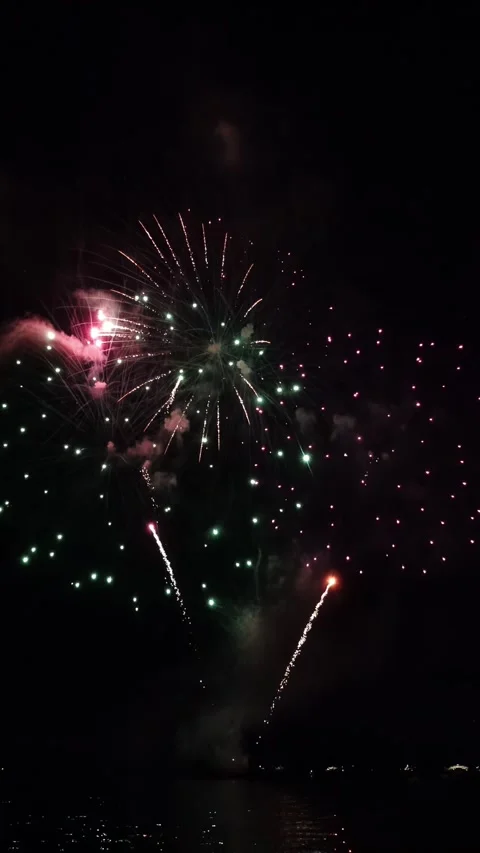 Stunning fireworks display exploding over water at night with colorful spar.. Stockbeeldmateriaal 339388453