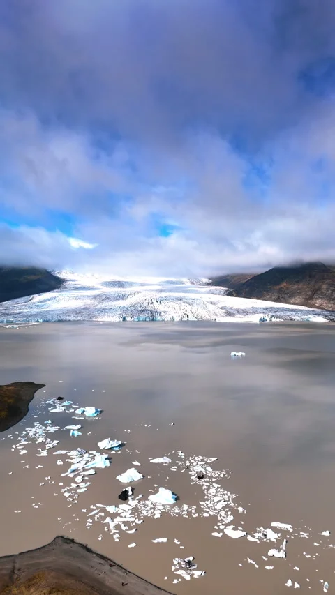 Stunning glacier descends into the waterscape of a cocoa color with some ice pie Stock Footage 285961178