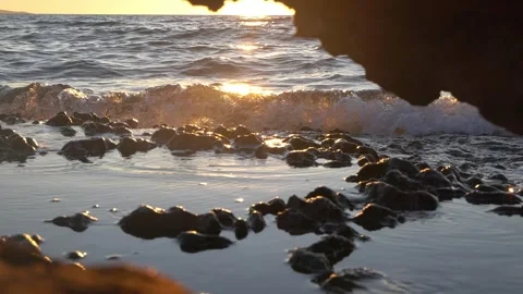 Stunning golden sunset shining through a rocky sea cave arch. Stock Footage 337405596