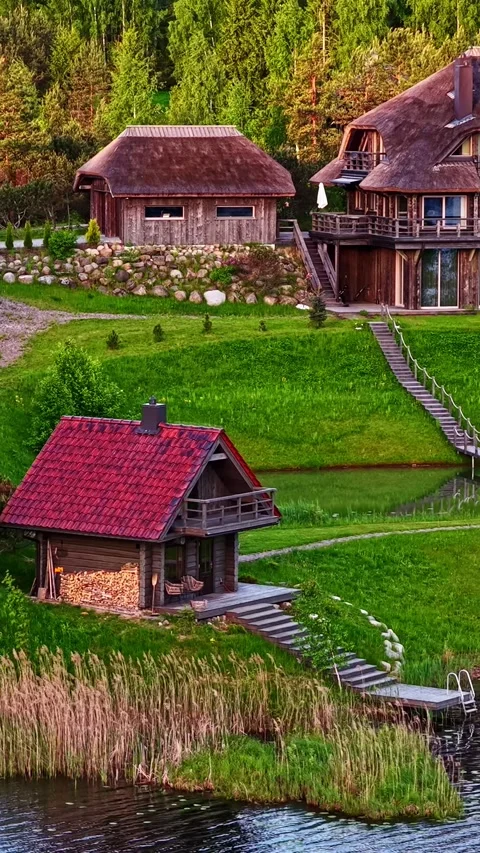 Stunning high-angle vertical drone shot of a cozy waterfront cabin with a red Видео 336622469