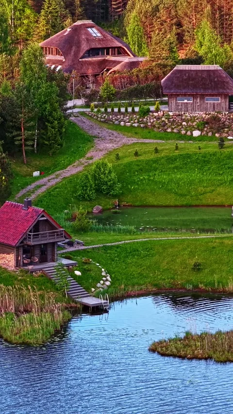 Stunning high-angle vertical drone shot of a cozy waterfront cabin with a red 스톡 동영상 336622573