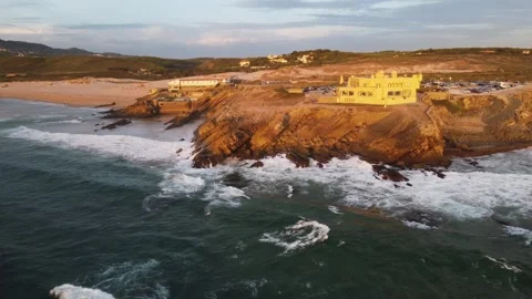 Stunning highangle shot capturing seaside home amidst wild ocean waves and rocky Stock Footage 325506195