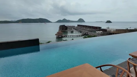 Stunning infinity pool overlooking the ocean and distant islands on a cloudy day 库存影片 343390818